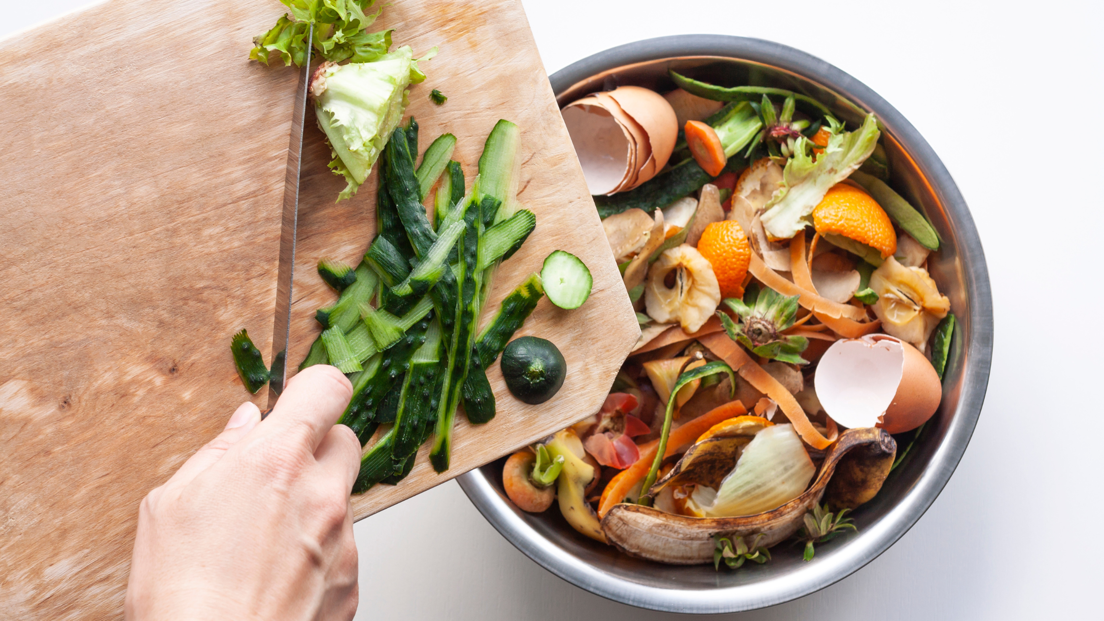 A close up of someone's hands scraping food waste into a bin